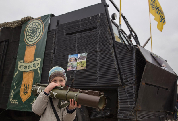 Ребенок с гранатометом на фоне эмблемы лагеря «Азовец»