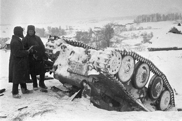 Два красноармейца стоят рядом с перевернутым немецким танком, подбитым в сражении под Москвой.