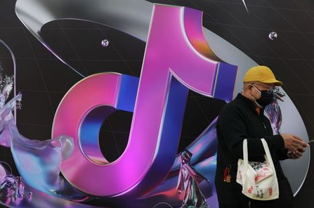 A man stands near a giant sign of Chinese company ByteDance's app TikTok, known locally as Douyin, during China Fashion Week, in Beijing, China March 31, 2021. REUTERS/Tingshu Wang