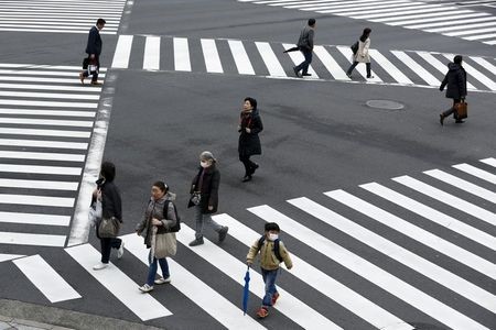 People cross a street in the Ginza shopping district in Tokyo, Japan, March 24, 2016. Japan's consumer inflation was flat in the year to February as low energy costs and weak consumption put a lid on price growth, keeping the central bank under pressure to top up stimulus even after easing policy less than two months ago. REUTERS/Thomas Peter