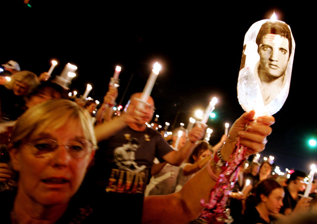 A woman holds an image of Elvis Presley during a candlelight vigil to mark the 28th anniversary of Elvis Presley's death during Elvis Week 2005 at Graceland August 15, 2005 in Memphis, Tennessee. Thousands of people from around the world have descended on Memphis to celebrate the life of Presley, who died August 16, 1977. (Photo by Carlo Allegri/Getty Images)