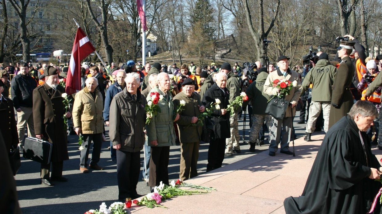 В первых рядах после богослужения в церкви — бывшие члены латышского добровольческого легиона СС, пастор и депутаты. К памятнику Свободы они возлагают цветы, поют гимн Латвии и песни легионеров.