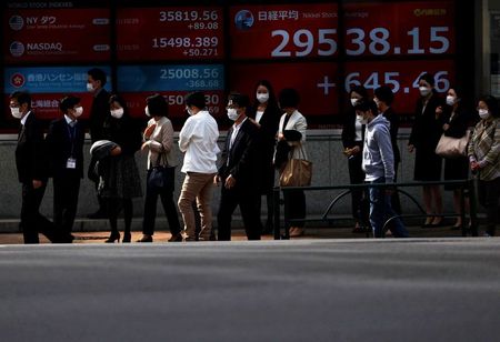 Passersby wearing protective face masks are seen in front of an electronic board showing Japan's Nikkei share average, amid the coronavirus disease (COVID-19) pandemic, in Tokyo, Japan November 1, 2021. REUTERS/Issei Kato