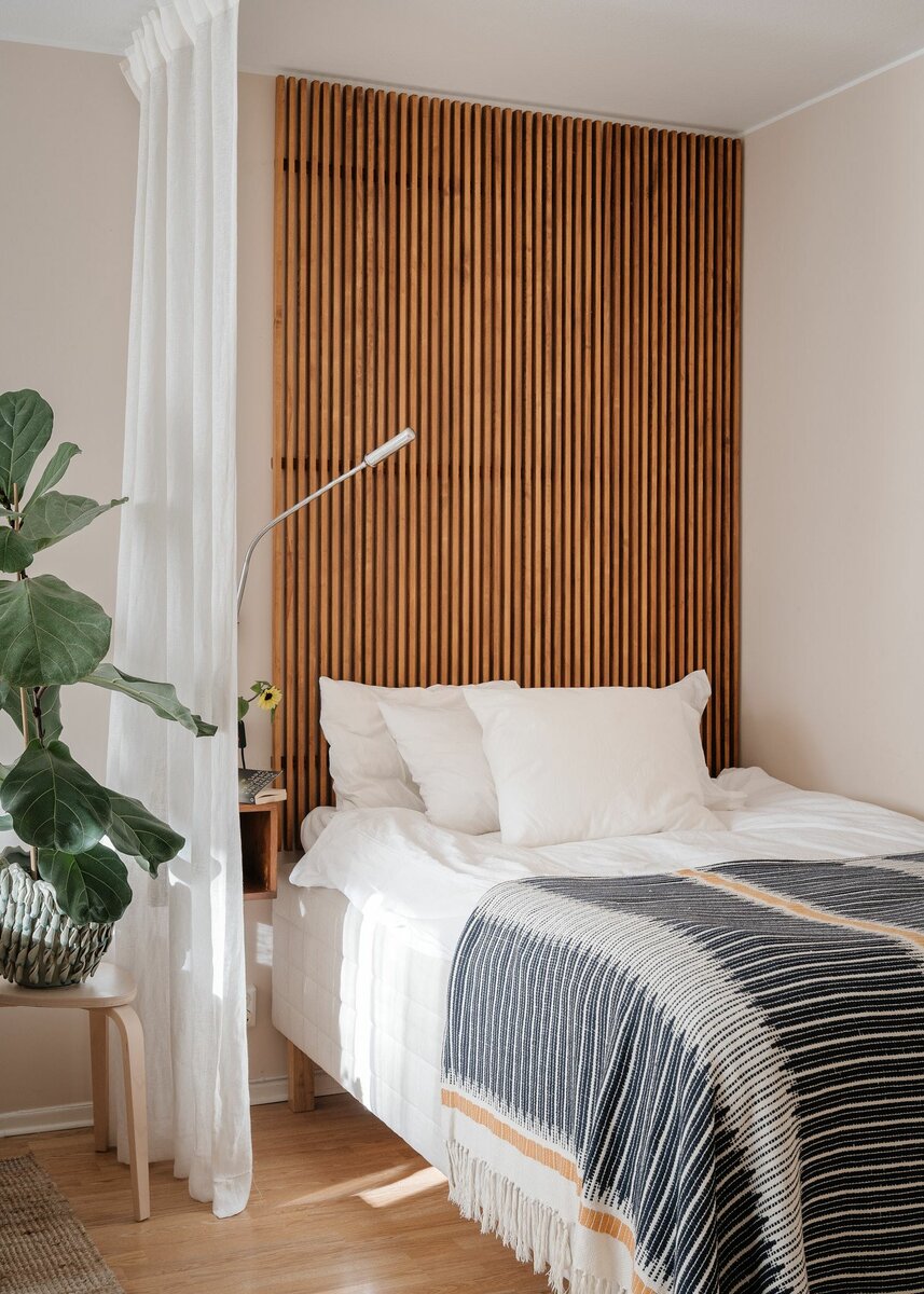 Деревянные рейки у изголовья кровати — очень удачная идея. Они помогают зонировать и отделить спальню от остального пространства