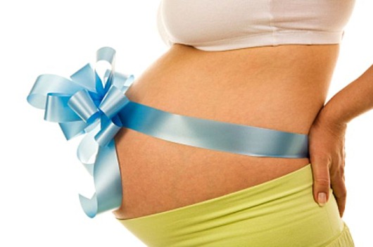 34 weeks pregnant belly with a blue bow against a white background