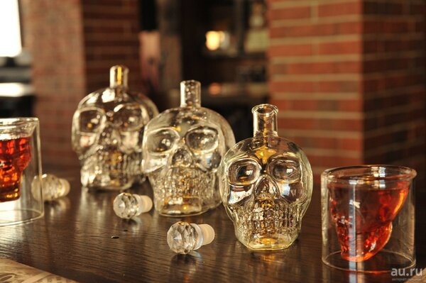 Графины для крепкого алкоголя и стакан в форме хрустального черепа.