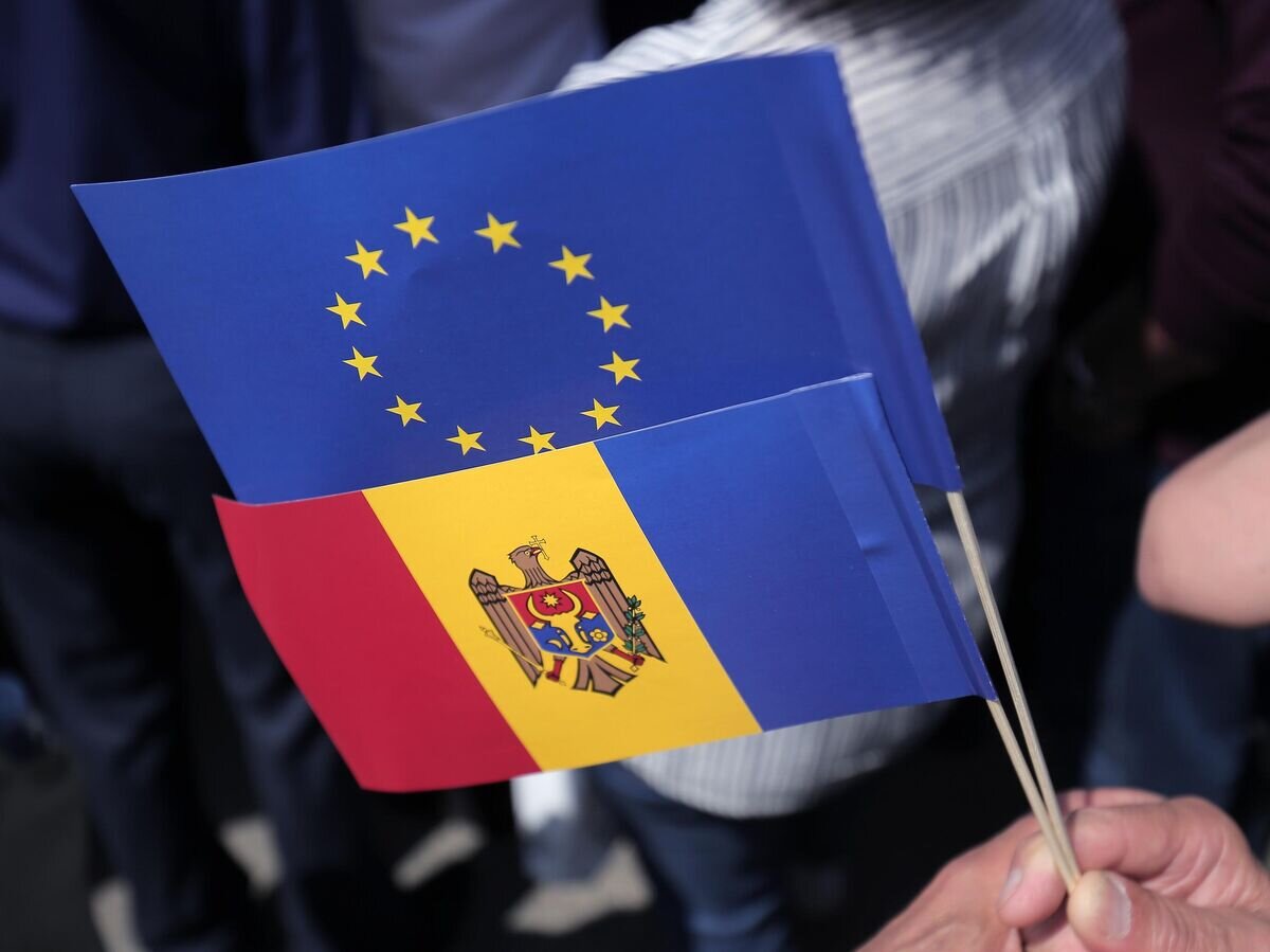    Флаги Молдавии и Евросоюза в руках одного из участников митинга на площади Великого Национального Собрания в Кишиневе© Sputnik / Дмитрий Осматеско