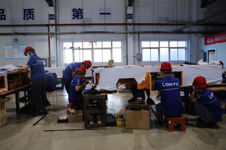 Employees work on assembling automated guided vehicles (AGV) at a Lonyu Robot Co factory in Tianjin, China, September 7, 2021. Picture taken September 7, 2021. REUTERS/Tingshu Wang