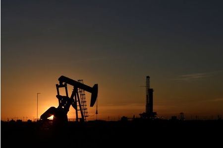 A pump jack operates in front of a drilling rig at sunset in an oil field in Midland, Texas U.S. August 22, 2018. Picture taken August 22, 2018. REUTERS/Nick Oxford
