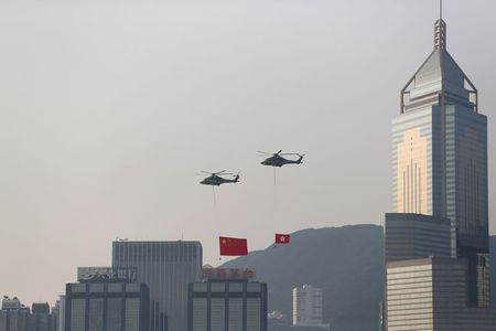 Helicopters carrying China's national flag and Hong Kong's flag fly past the skyline of Victoria Harbour on China's National Day in Hong Kong, China October 1, 2019. REUTERS/Athit Perawongmetha