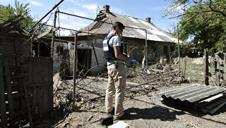 Сотрудник ОБСЕ осматривает двор жилого дома, пострадавший в результате обстрела. Архивное фото
