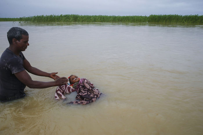 A Man Floats His Dead Nephew Away In The Koshi River Outside A Village In Nepal, After The Family Could Not Find Any Dry Land To Bury The Child