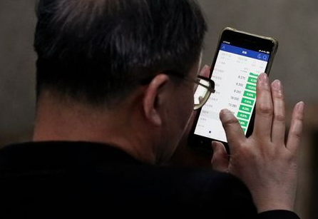 An investor checks stock information on a mobile phone at a brokerage house in Shanghai, China May 6, 2019. REUTERS/Aly Song