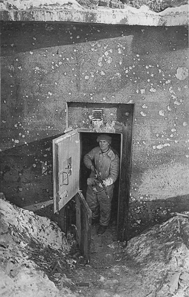 Боец РККА, вооруженный автоматом Федорова, осматривает финский ДОТ-капонир в районе Муурила, захваченный советскими войсками во время советско-финской войны 1939-1940 гг.