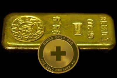 An ounce of gold coin is pictured in front of a 500g ingot at Jolliet numismatic shop in Geneva November 19, 2014. Support among Swiss voters for a referendum proposal that would force a huge increase in the central bank's gold reserves has slipped to 38 percent percent, an opinion poll showed on Wednesday, falling short of the majority backing it needs to become law. Under the "Save our Swiss gold" proposal, the Swiss National Bank (SNB) would be banned from selling any of its gold reserves and would have hold at least 20 percent of its assets in the metal, compared with 7.8 percent last month. REUTERS/Denis Balibouse (SWITZERLAND - Tags: POLITICS BUSINESS)