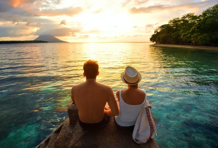 Couple sitting over the water watching a tropical sunset