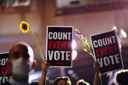 Activists hold up flowers and signs stating "COUNT EVERY VOTE" across the street from where votes are still being counted, two days after the 2020 U.S. presidential election, in Philadelphia, Pennsylvania, U.S. November 5, 2020. REUTERS/Mark Makela