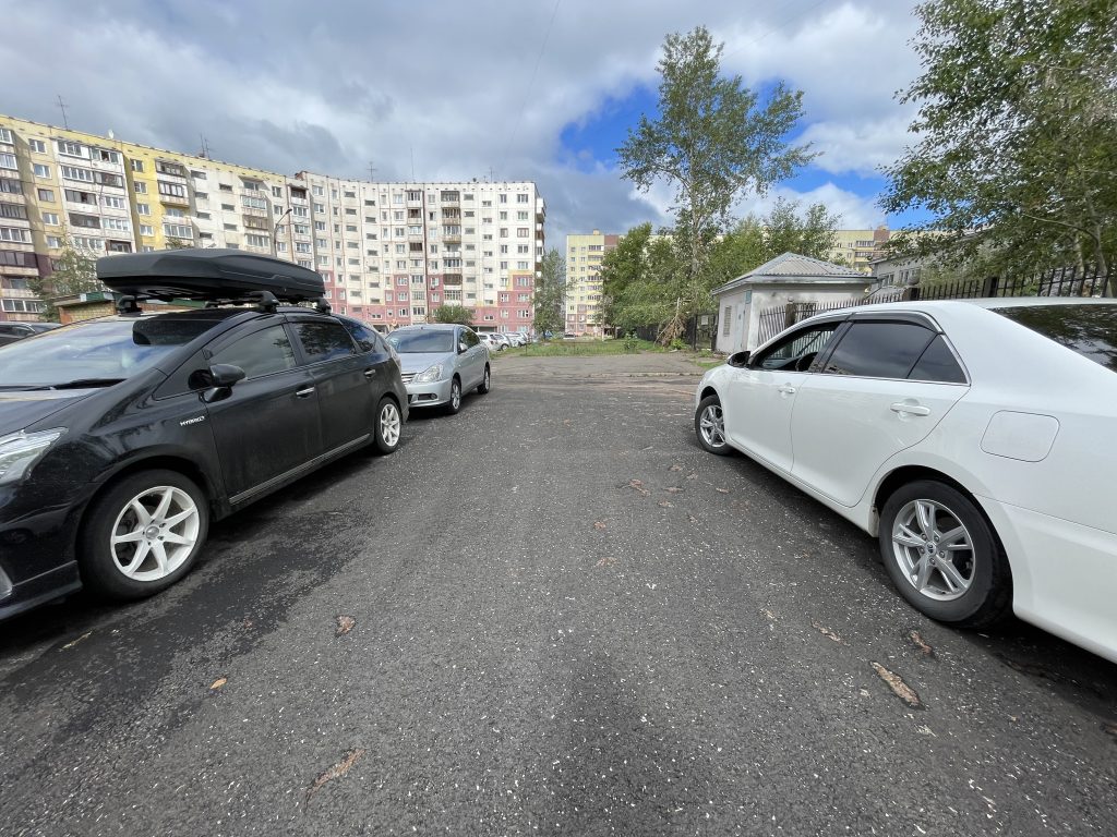 Запаркованные автомобили на фоне жилых зданий