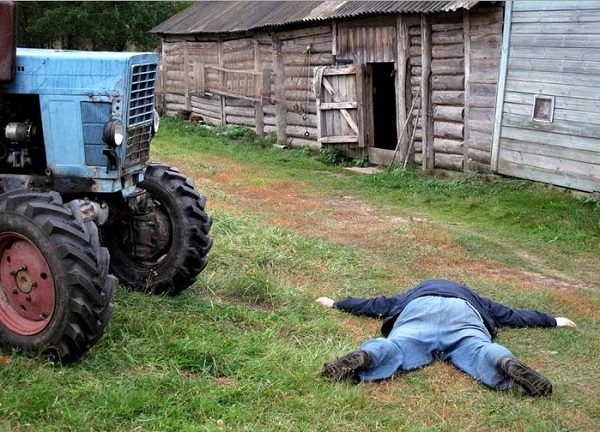 Мужчина лежит на земле у трактора
