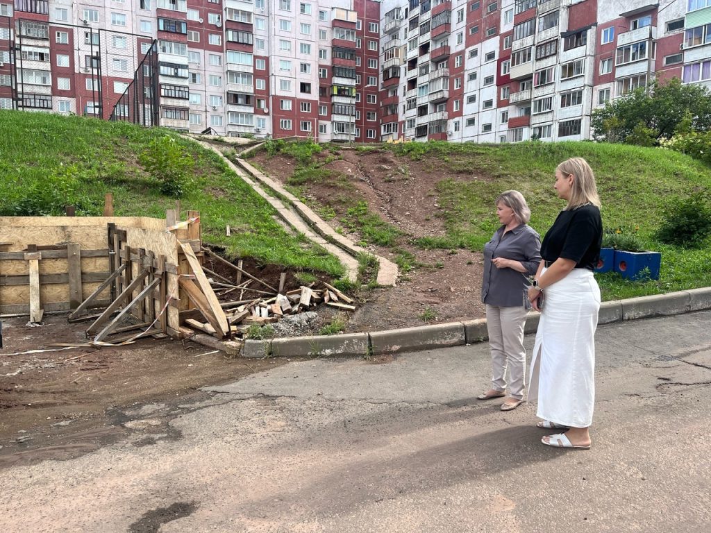 Женщины осматривают стройку возле многоквартирного дома.