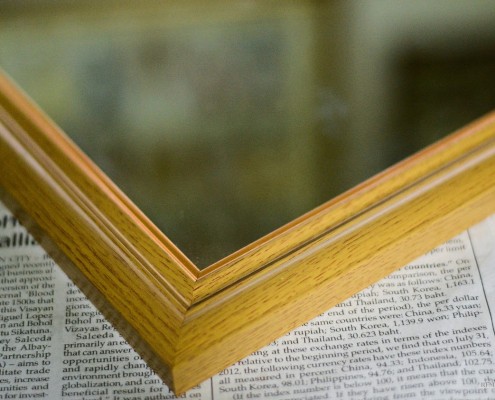 Угол деревянной рамы для зеркала на газете