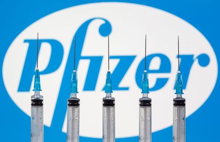 Syringes are seen in front of a displayed Pfizer logo in this illustration taken, November 10, 2020. REUTERS/Dado Ruvic/Illustration