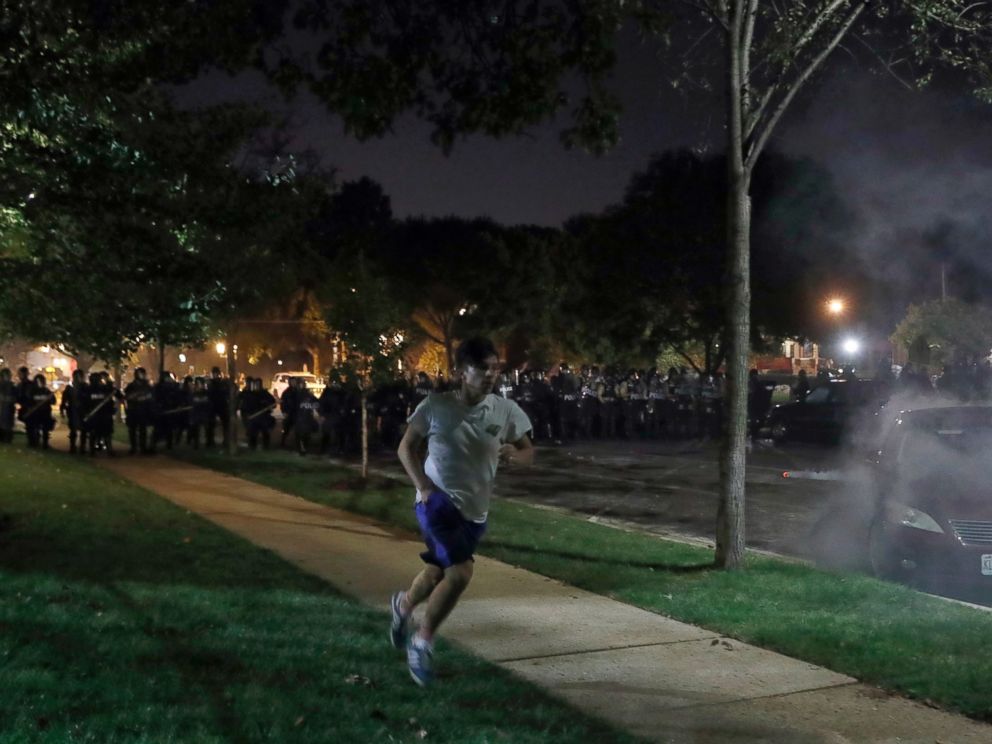 A protester runs from the police, Friday, Sept. 15, 2017, in St. Louis, as protesters rally around the home of St. Louis Mayor Lyda Krewson, after a judge found a white former St. Louis police officer, Jason Stockley, not guilty of first-degree murde