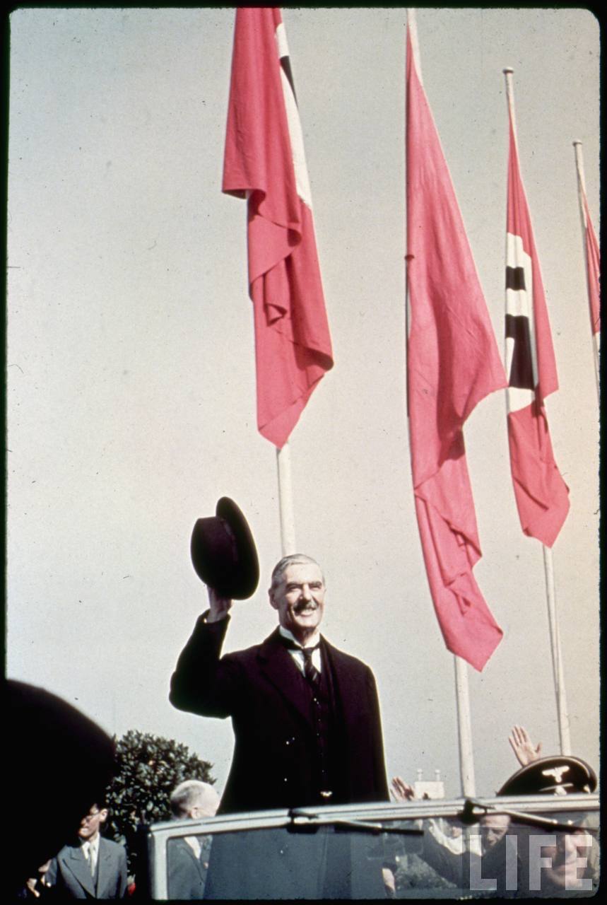 Британский премьер Невилл Чемберлен под сенью нацистских знамен. Прибыл в Мюнхен договариваться с Гитлером о сдаче ему Чехословакии. 1938 г.