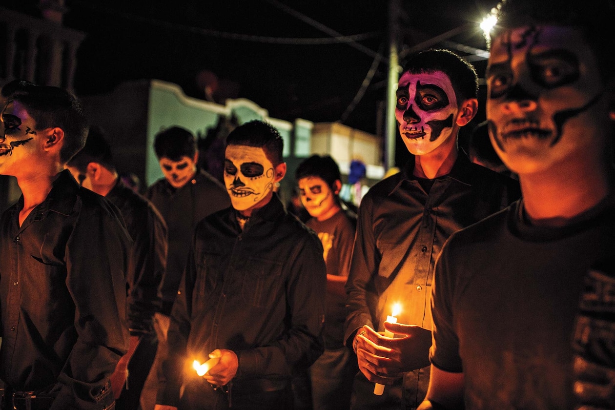 Община в Мексике, чьи лица раскрашены в виде черепов, празднует День мертвых со свечами