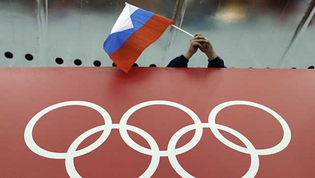 Болельщик держит российский флаг над логотипом олимпийских игр. Архивное фото