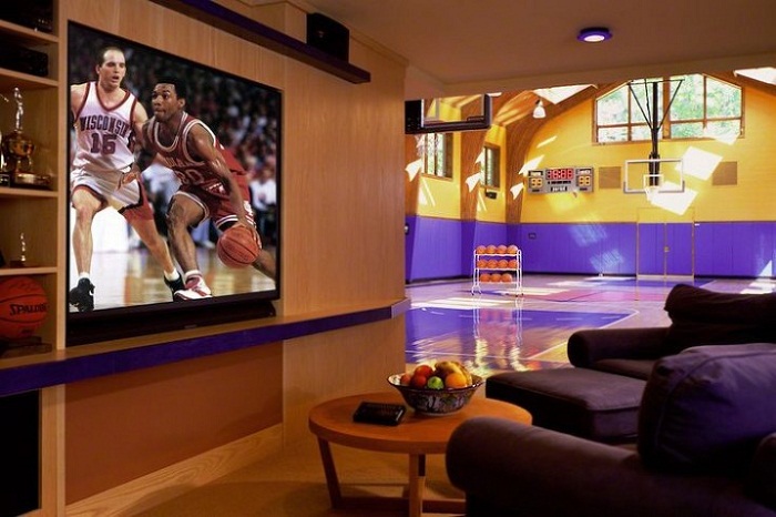 Уютная гостиная с большой плазмой дополнена баскетбольной площадкой, которая граничит с ней.