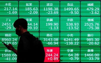 FILE PHOTO: A man wearing a protective face mask walks past a stock quotation board outside a brokerage, amid the coronavirus disease (COVID-19) outbreak, in Tokyo, Japan May 11, 2021. REUTERS/Issei Kato