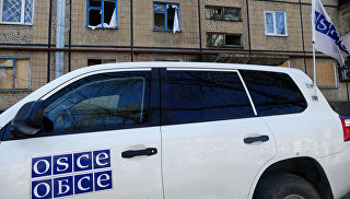 Автомобиль представителей ОБСЕ у жилого дома, поврежденного в результате обстрелов, в Киевском районе Донецка. Архивное фото