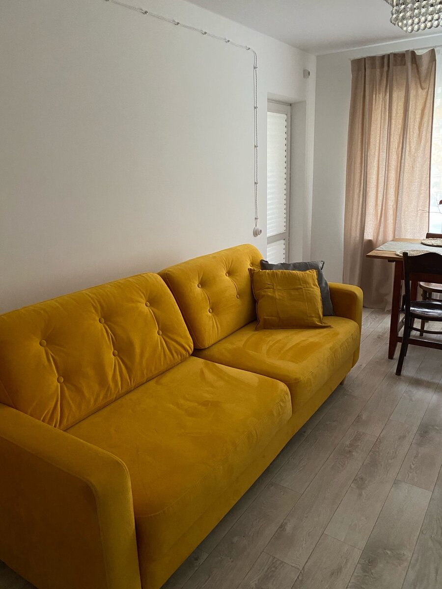 Рядом с обеденным столом стоит диван горчичного цвета, который поддерживает осеннюю атмсферу в доме