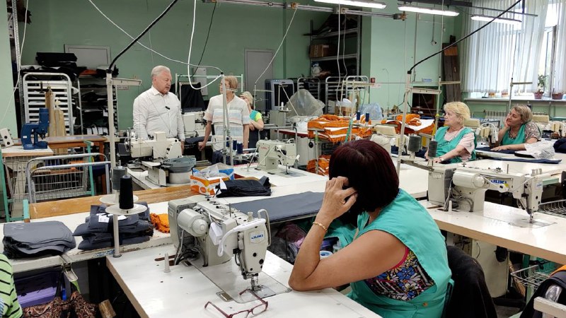 Рабочие в швейной мастерской за швейными машинами