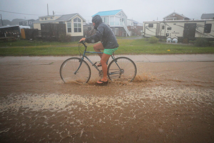 Велосипедист едет по затопленной улице, когда тропический шторм Генри приближается к Южному Кингстауну, Род-Айленд