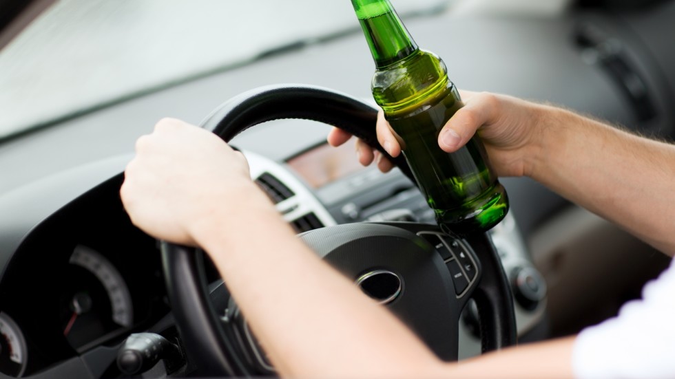 man drinking alcohol while driving the car