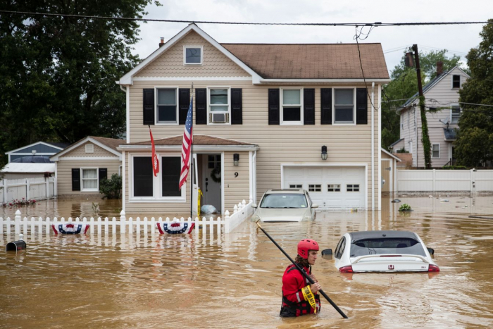 Член спасательной команды New Market Volunteer Fire Company пробирается через паводок после внезапного наводнения, когда тропический шторм «Генри» обрушился на берег в Хелметте, штат Нью-Джерси