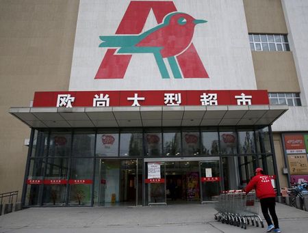 FILE PHOTO: An employee carries shopping carts into Sun Art Retail Group's Auchan hypermarket store in Beijing, China, November 9, 2015. REUTERS/Kim Kyung-Hoon/File Photo