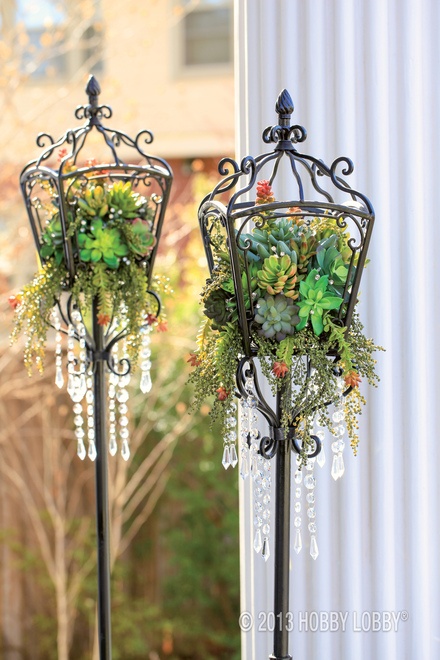Get green scene ambiance at light speed with a succulent-filled lantern. For this  look, we used raffia to anchor a ball of floral foam to the metal. Then we tucked in a variety of stems, along with bits of made-to-dangle greenery. To finish, we added diamond picks and hanging gems.: 