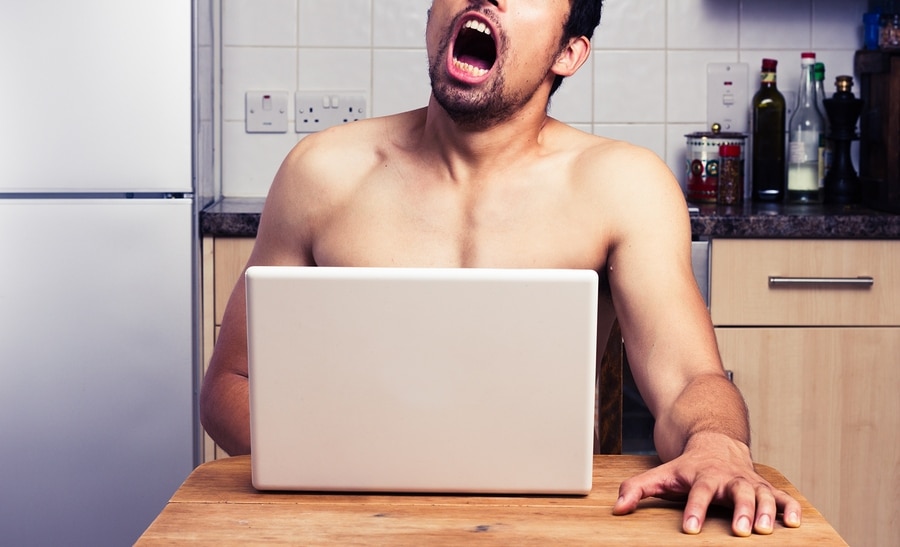 Young naked man watching porn in his kitchen