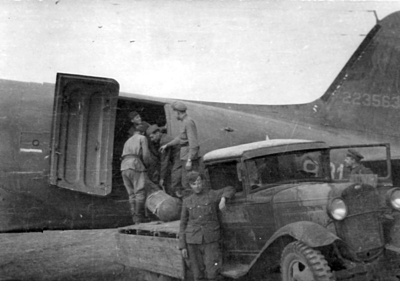 Советские солдаты укладывают в транспортный самолет DC-3 грузы для партизан на Украине из кузова грузовика ГАЗ-АА.