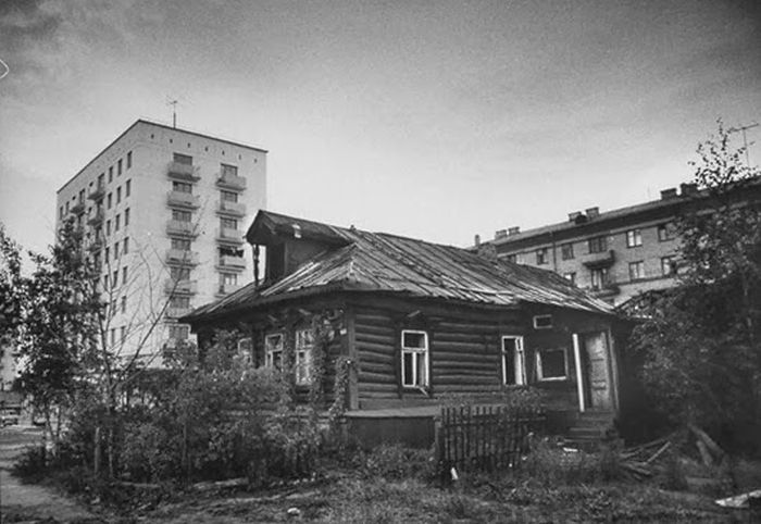 Опустевшая изба на фоне городских построек. Опустевшая изба на фоне городских построек.