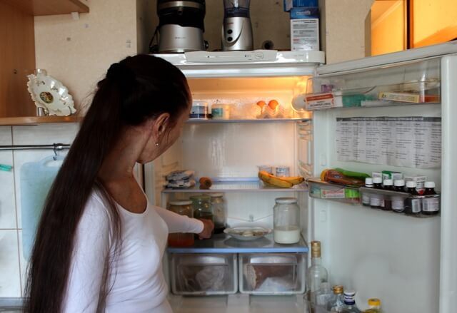  70-летняя женщина показывает свой холодильник