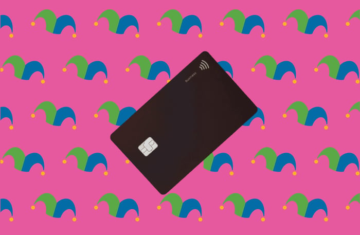 A black credit card against a pink background