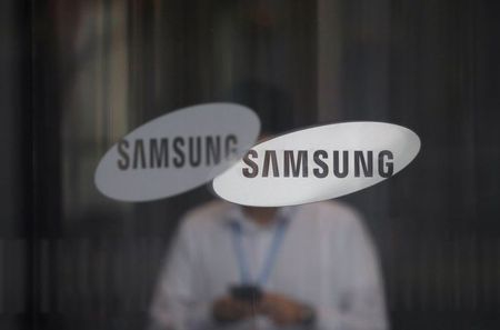 An employee using his mobile phone walks past the logo of Samsung Electronics at its office building in Seoul, South Korea, August 25, 2017. REUTERS/Kim Hong-Ji