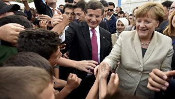 Премьер-министр Турции Ахмет Давутоглу и канцлер Германии Ангела Меркель встречают беженцев