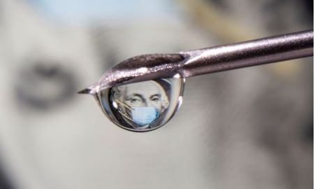 George Washington is seen with a printed medical mask on a one dollar bill reflected in a drop on a syringe needle in this illustration taken November 9, 2020. REUTERS/Dado Ruvic/Illustration