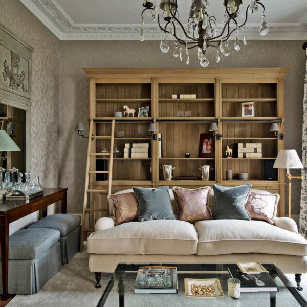 Lovely-living-room-sofa-with-glass-table-on-rug-also-wooden-side-table-with-gray-puffs-and-decorative-mirror-along-with-rustic-buffet-and-classic-lamps-decoration