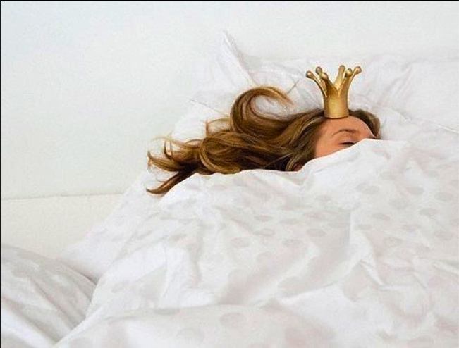 Фото Девушка с короной на голове спит в белой постели